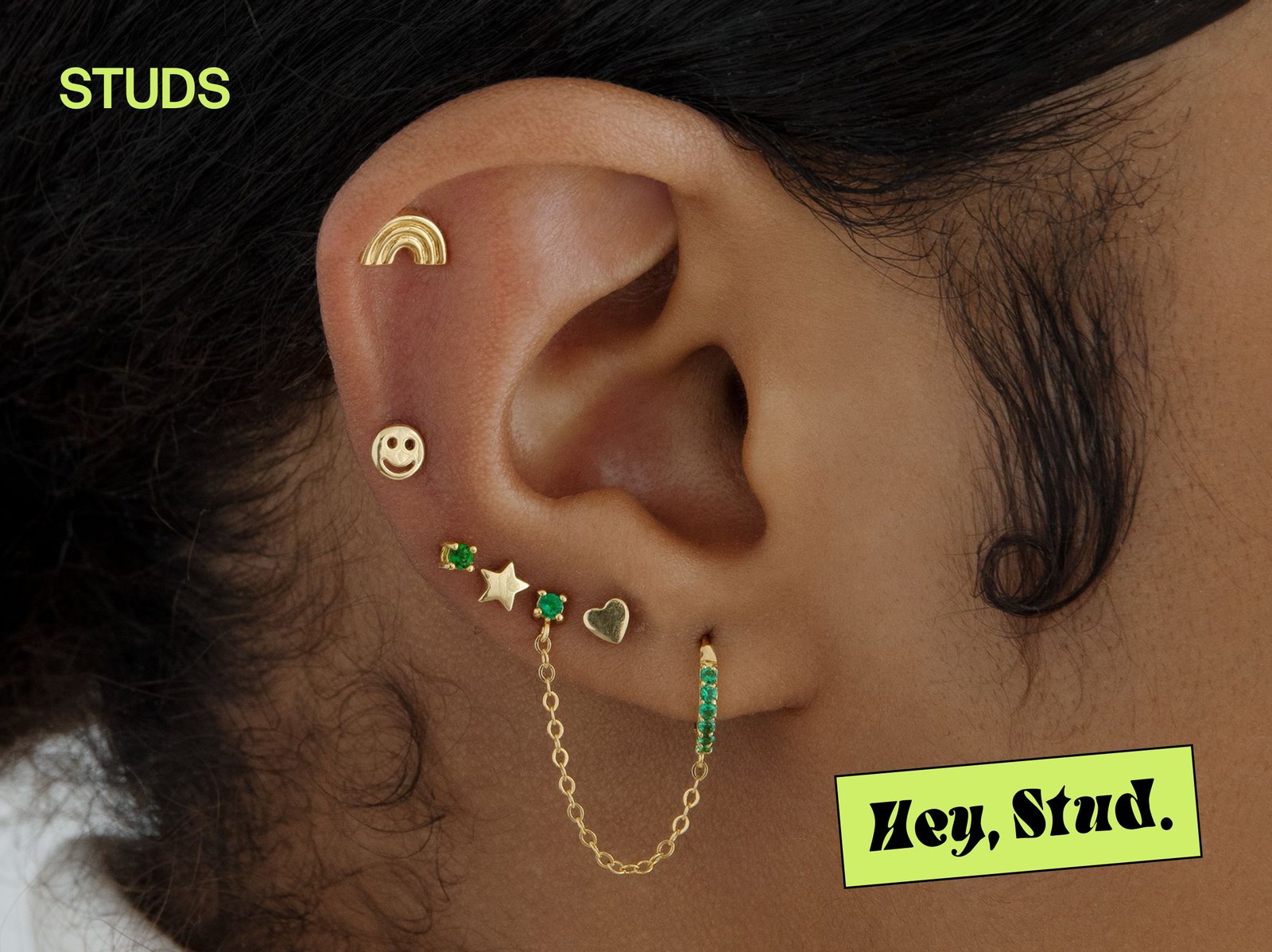 Studs: an ear stacked with gold studs and a Hey, Stud. sticker