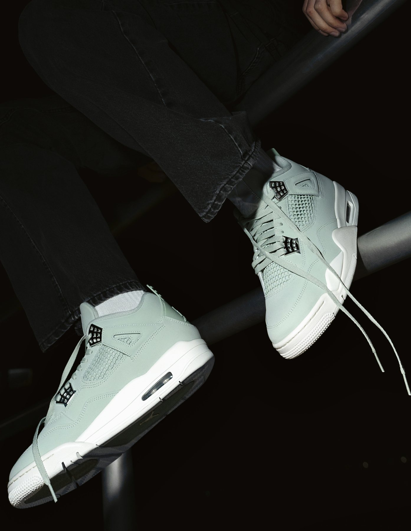 Sneaker shoot: Model seated on a metal rail in the mint pair, laces loose