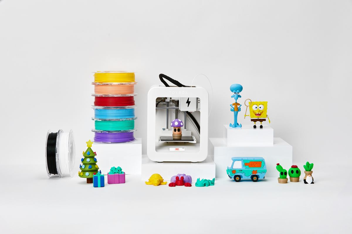 Toybox 3D printer — hero group shot with colorful filaments and 3D-printed objects